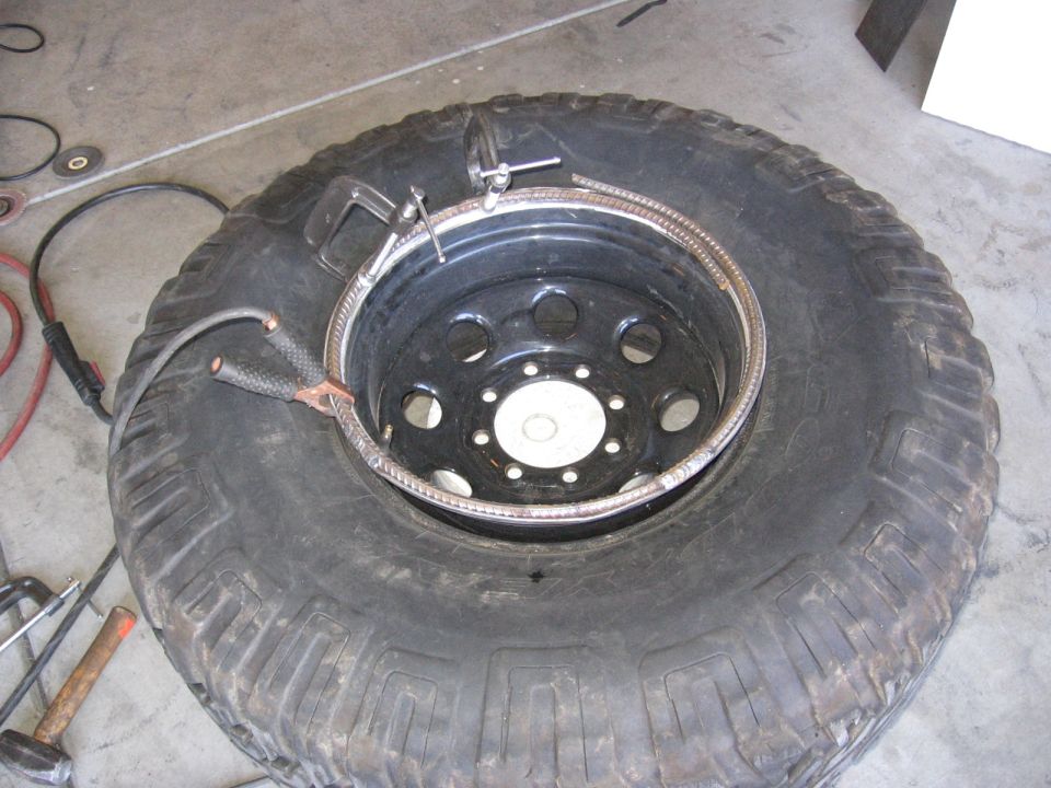 Beadlock ring being welded onto a black steel wheel with mud-terrain tire