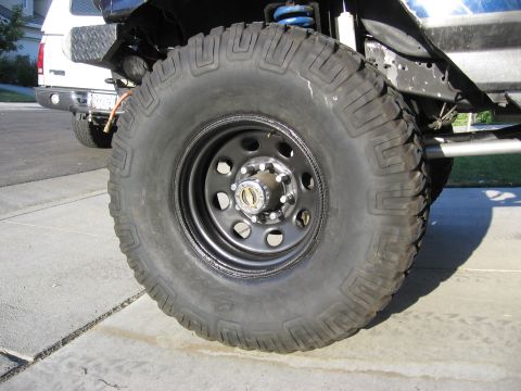 1994 Ford Bronco - Close-up of a large tire and wheel on a modified vehicle, with another vehicle visible behind it.