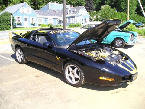 1984 Pontiac Fiero - A black 1994 Pontiac Firebird Trans Am is parked with its hood open, alongside a vintage teal car.