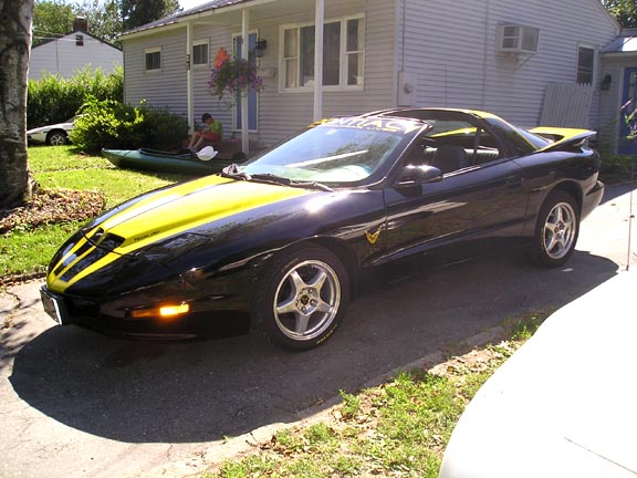 Black 1994 Pontiac Trans Am with yellow racing stripes on hood and roof, parked in driveway