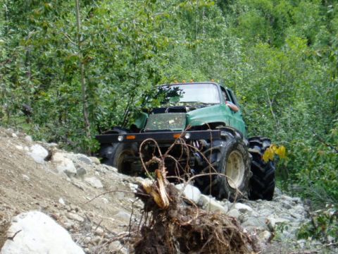 2000 Ford E350 - Modified truck navigates a challenging rocky terrain in a wooded area.