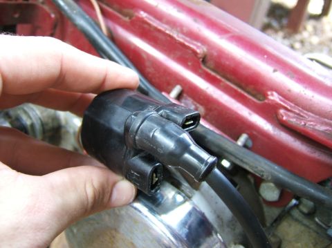 1996 Ford Probe - Close-up of a motorcycle ignition coil being held by a hand, with part of the red frame visible.