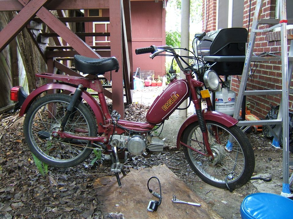 Maroon moped with 'Eagle' logo on gas tank, parked outdoors
