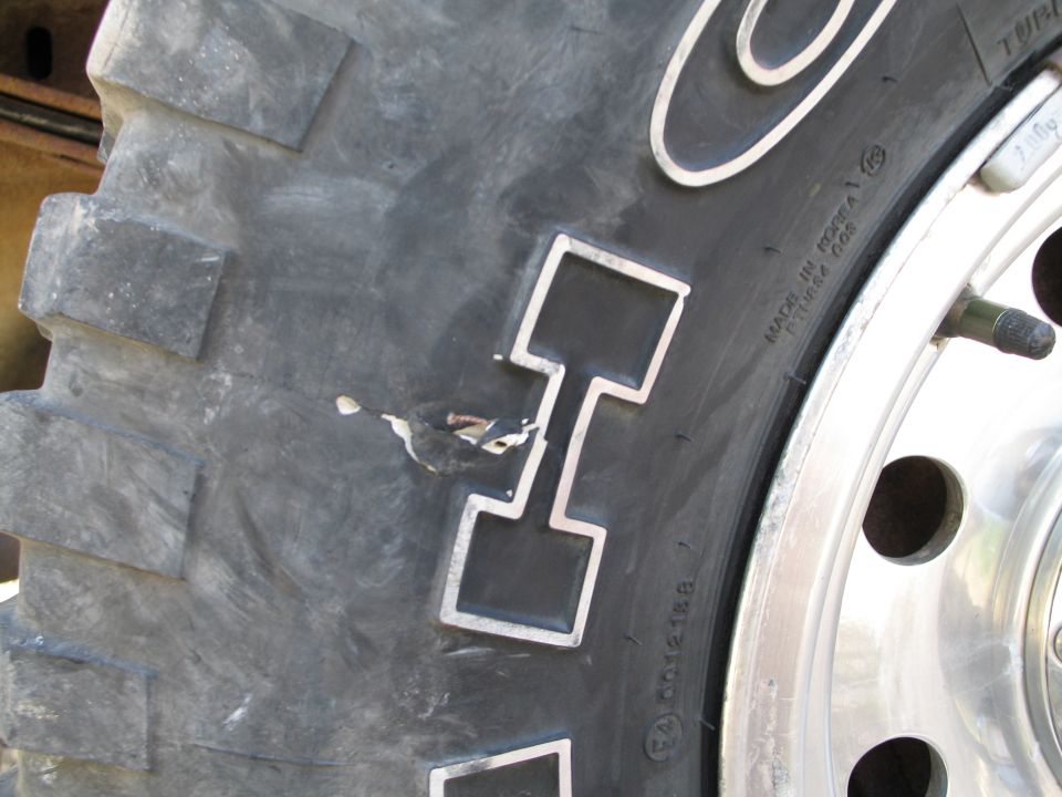 Close-up of a tire with a gouge in the tread. Text on the tire reads 'MADE IN KOREA'