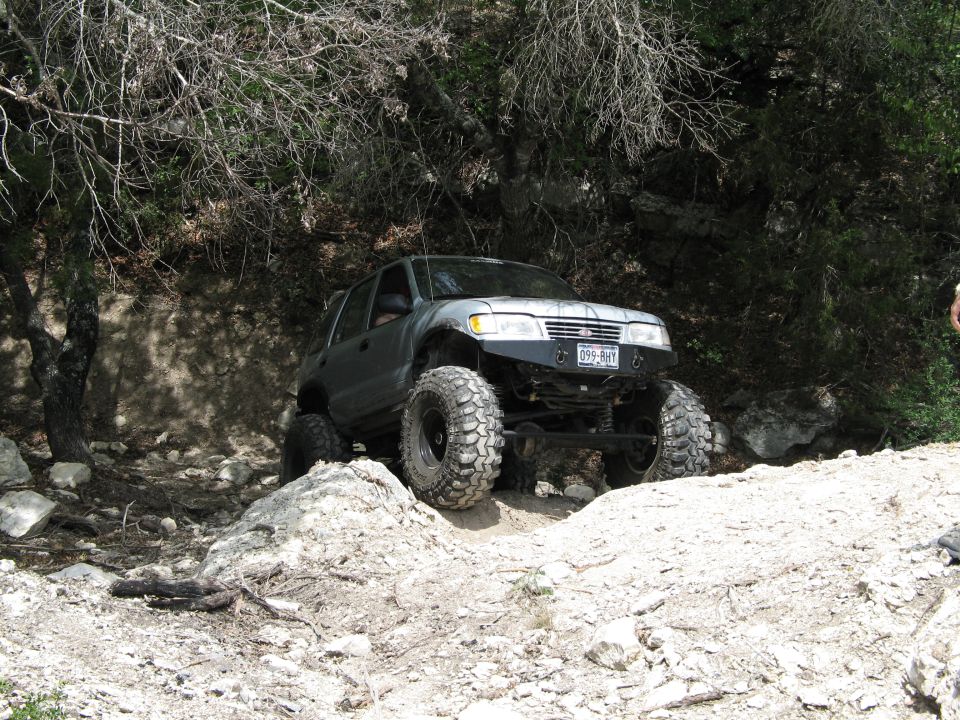 Silver SUV with oversized tires navigating a rocky trail