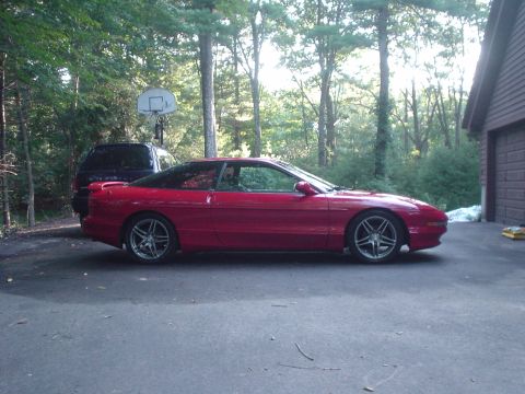 1995 Ford Probe - Side view of a red 1995 Ford Probe parked in a driveway with a dark SUV behind it.