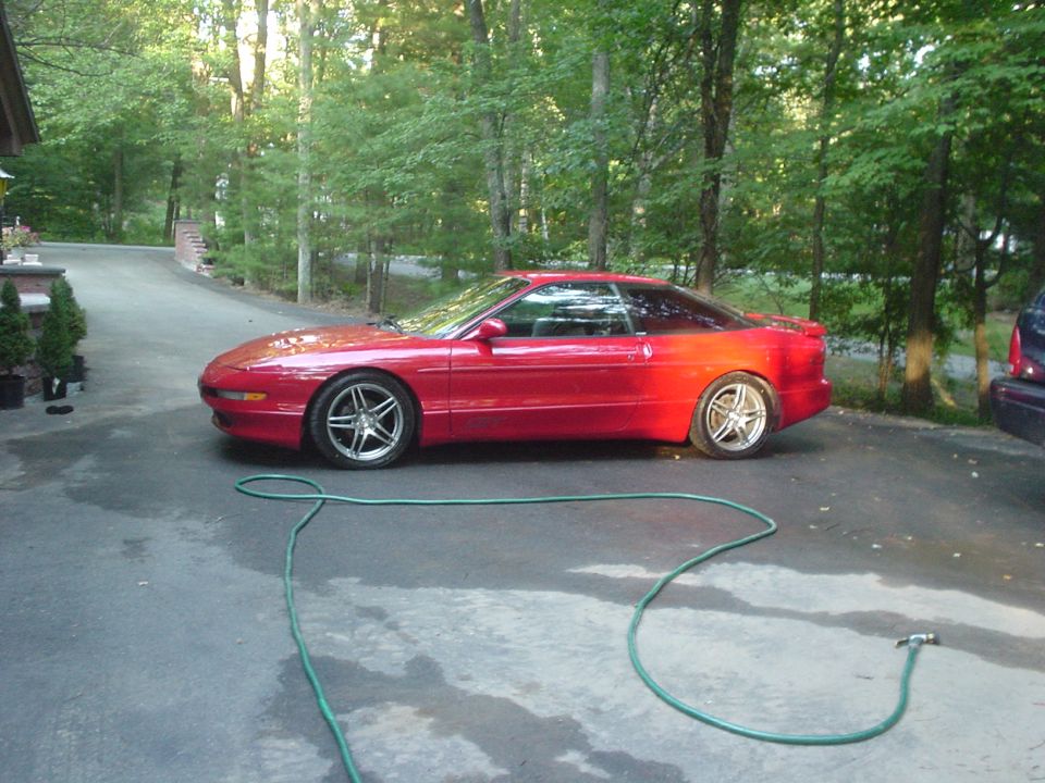 Red 1995 Ford Probe parked on driveway with a green hose on the ground