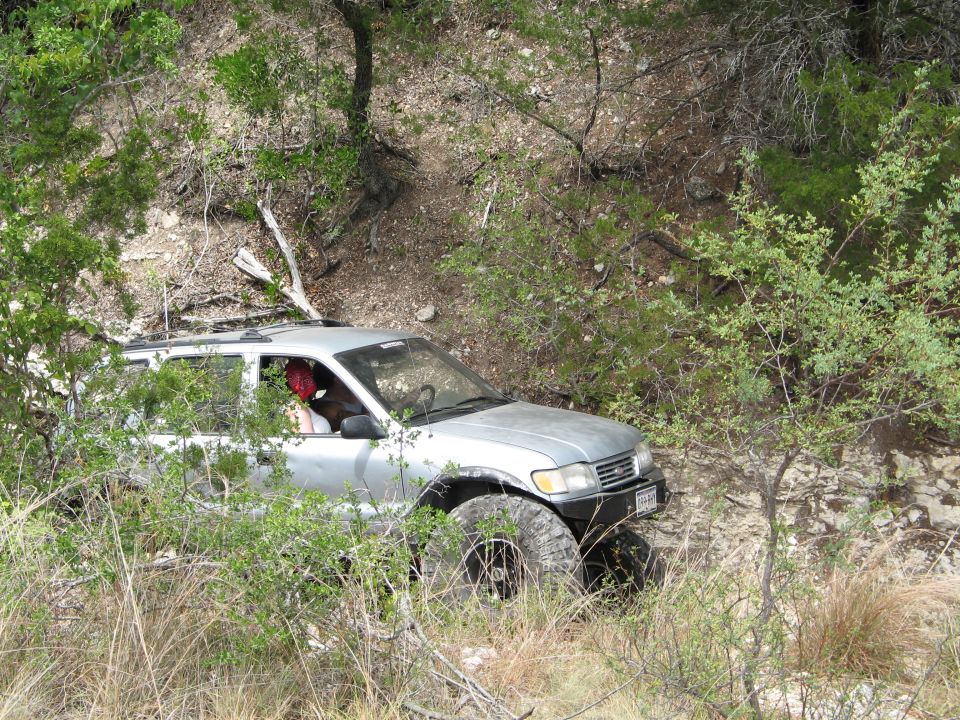 Silver SUV navigating a rocky, wooded trail