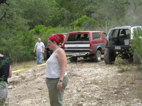 1995 Ford Bronco - A red and gray Ford Bronco is parked on a dirt road with other off-road vehicles.