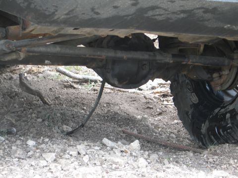 1995 Ford Bronco - Close-up view of the underside of a vehicle, focusing on the rear axle and tire assembly.