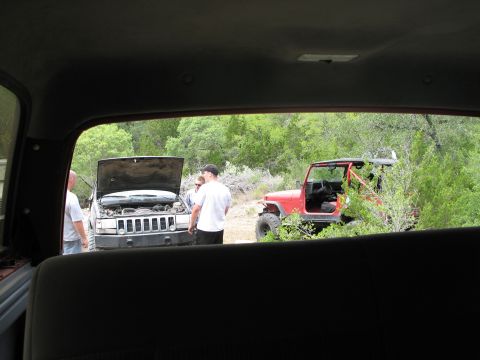 1995 Ford Bronco - Two off-road vehicles are parked in a natural setting with people gathered around one of them.