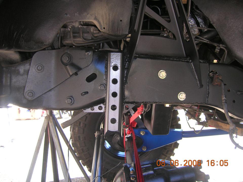 Undercarriage showing black frame, blue suspension links, and adjustable bracket near a tire