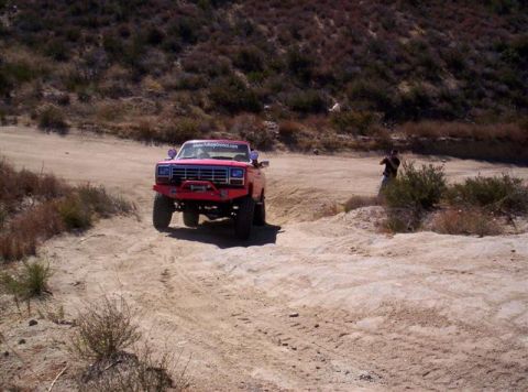 1995 Ford Bronco - Modified red Ford Bronco navigating an off-road trail.