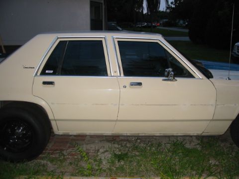 1985 Ford LTD Crown Victoria - A tan sedan with a distinctive body style is parked outdoors.