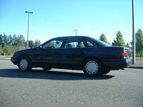 1995 Ford Taurus - Side profile of a 1995 Ford Taurus sedan under a clear blue sky.