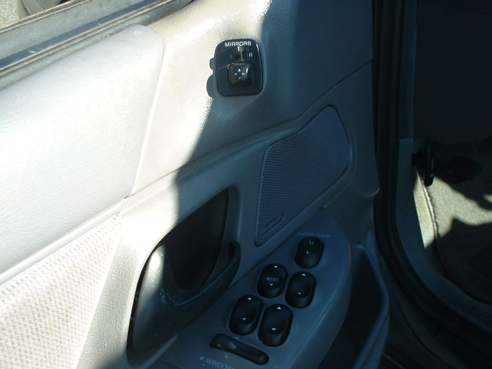 Interior door panel with window and lock controls, speaker, and mirror adjustment