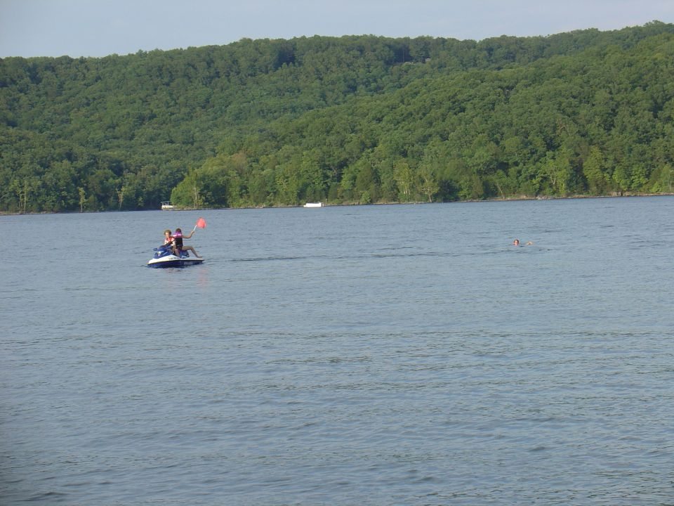 Jet ski with two people on a lake with a wooded hill in the background