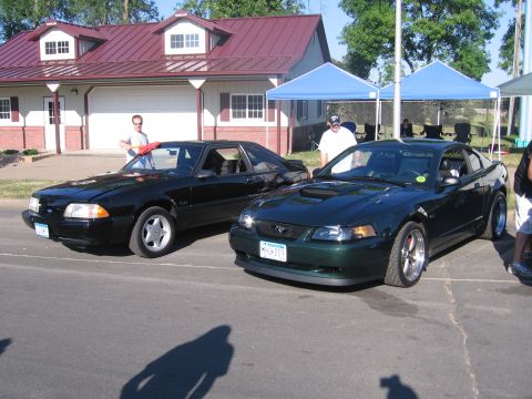 1989 Ford Mustang - Two Ford Mustangs, one from the late 90s and an older model, are parked side-by-side.