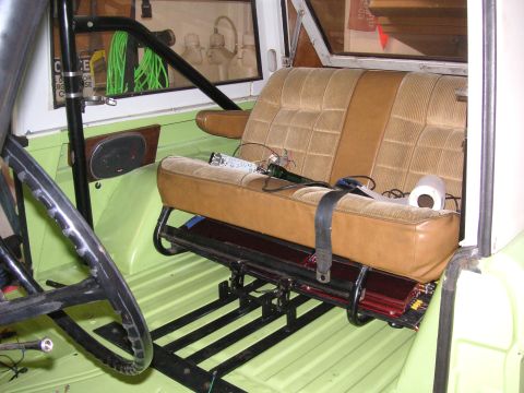 1999 Jeep Grand Cherokee - The interior of a vehicle shows a tan bench seat with a roll cage and a roll of toilet paper on the seat.