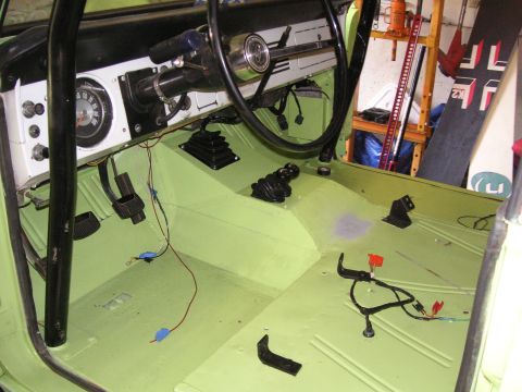 1999 Jeep Grand Cherokee - The interior of a vehicle shows exposed wiring and a roll cage, with a green painted floor and a watermark.