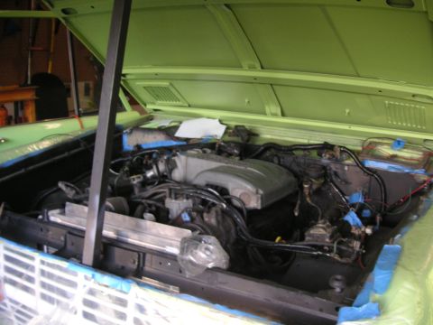 1999 Jeep Grand Cherokee - The engine bay of a vehicle, a V8 engine and green painted surfaces, with the Supermotors.net logo in the lower right corner.