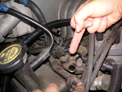 1999 Jeep Grand Cherokee - A close-up view of engine components, including hoses and a valve, with hands indicating specific parts.