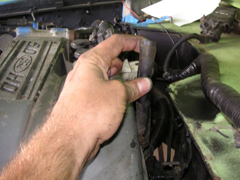 1999 Jeep Grand Cherokee - A hand manipulates a hose within a cluttered engine compartment, obscuring any clear vehicle identification.