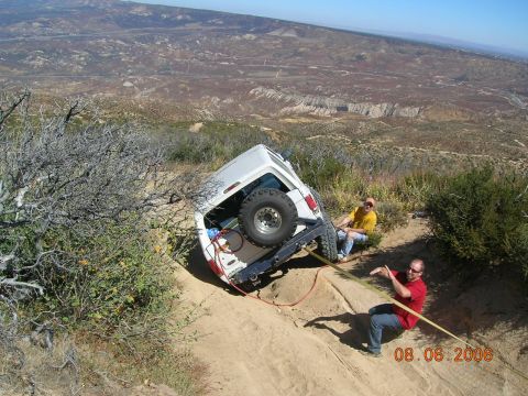 1985 Ford Bronco - Two men attempt to recover a white 1985 Ford Bronco stuck on a steep, rocky incline.