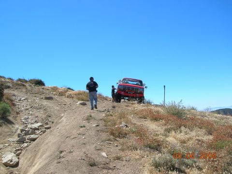 1985 Ford Bronco - A red pickup truck is parked on a dirt hill under a clear blue sky.