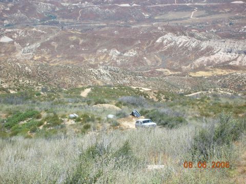 1985 Ford Bronco - Off-road vehicles traversing a dusty trail in a vast, arid landscape.