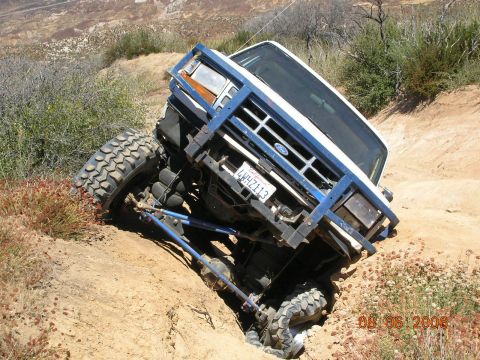1985 Ford Bronco - This modified Ford Bronco is navigating a steep, uneven dirt path in a dry, brushy environment.