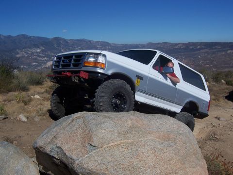 1985 Ford Bronco - A modified Ford Bronco navigates a rocky trail in a mountainous landscape.