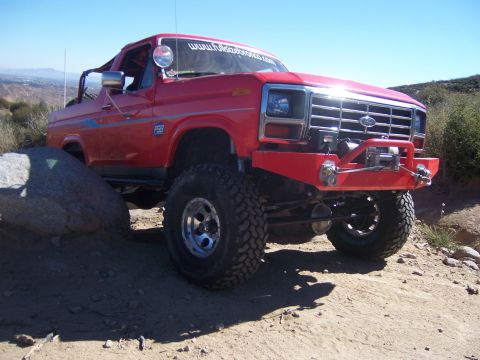 1985 Ford Bronco - This red 1985 Ford Bronco is equipped for off-road adventures with its lifted suspension, large tires, and front winch.