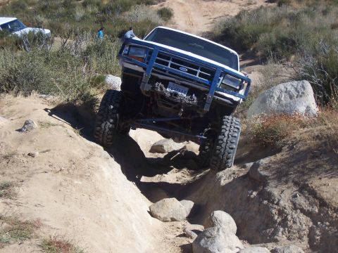 1985 Ford Bronco - Modified Ford Bronco navigating a steep, rocky trail with a second vehicle visible in the background.