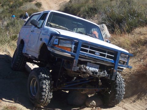 1985 Ford Bronco - A modified Ford Bronco navigates a rocky, off-road trail with steep inclines.