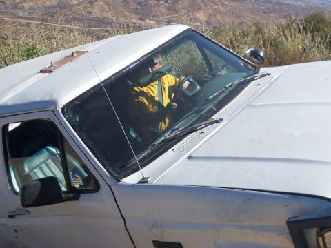 1985 Ford Bronco - Driver in a yellow shirt is visible inside the cab of a white pickup truck.