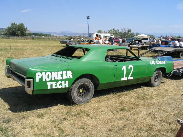 Green number 12 demolition derby coupe with Pioneer Tech lettering parked on grass