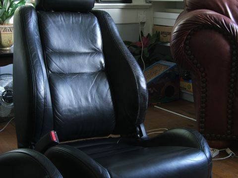 1996 Ford Probe - Close-up of black leather car seats, showing stitching and a red seatbelt buckle.