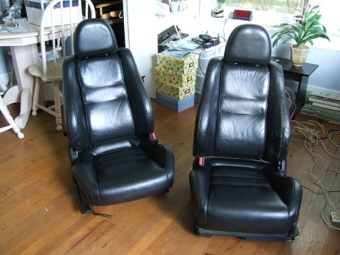 1996 Ford Probe - Pair of black leather car seats shown indoors on a wooden floor.