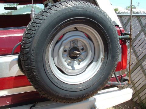 1990 Ford Bronco - A spare tire is mounted externally on the back of a red and white vehicle.