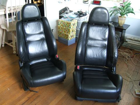 1996 Ford Probe - A pair of black leather car seats, likely from a sports car, are shown indoors on a wooden floor.