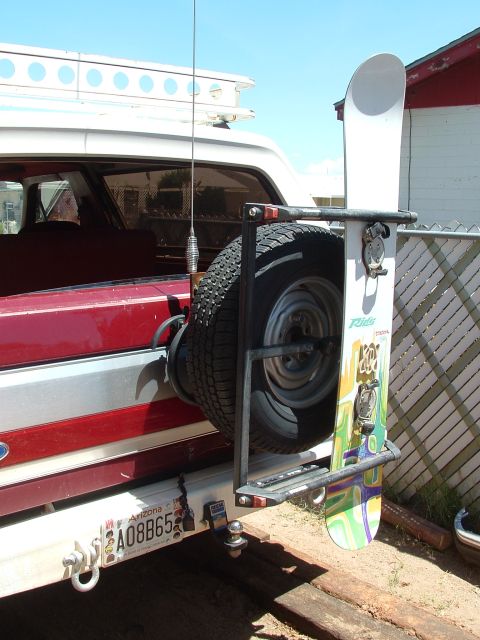 1990 Ford Bronco - A snowboard is mounted to a rack on the rear of a Ford Bronco, next to the spare tire.