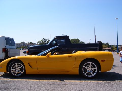1993 Ford Bronco - A yellow convertible sports car is parked next to a black pickup truck in a parking lot.
