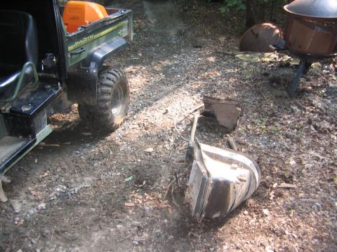 1979 Ford Bronco - A John Deere Gator utility vehicle is parked on a dirt path next to scattered metal parts.