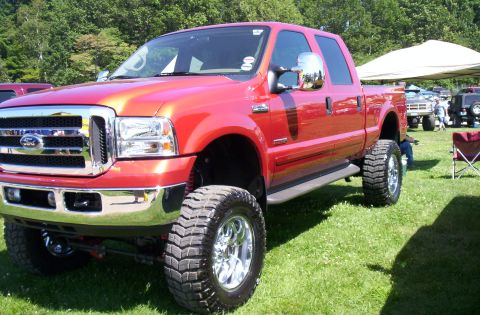 2006 Ford Supercrewzer - Red Ford F-250 Super Duty pickup truck with lifted suspension and large tires.