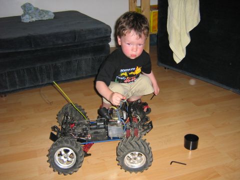 1995 Ford Bronco - A young boy is playing with a remote control monster truck indoors.