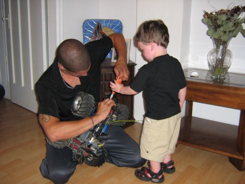 1995 Ford Bronco - A man and a young boy work on a remote control monster truck indoors.