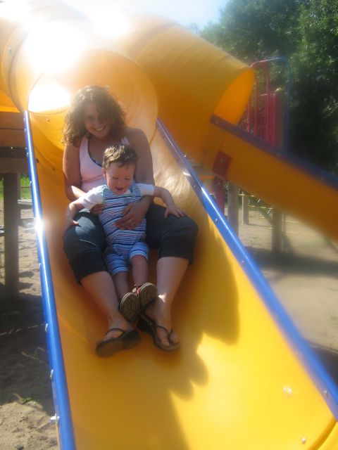 1995 Ford Bronco - A woman and a child slide down a yellow playground slide on a sunny day.