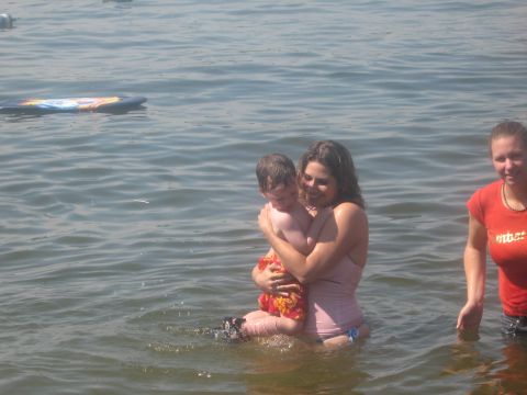 1995 Ford Bronco - A woman holds a child while standing in the water, with another woman in the background.