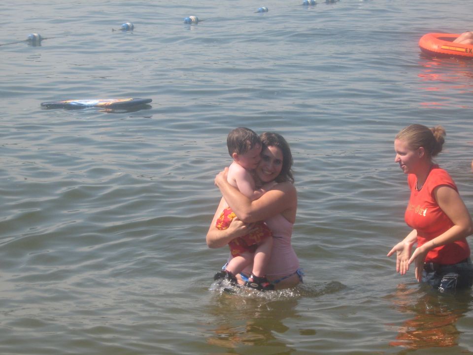 Woman holding child in water, another woman nearby